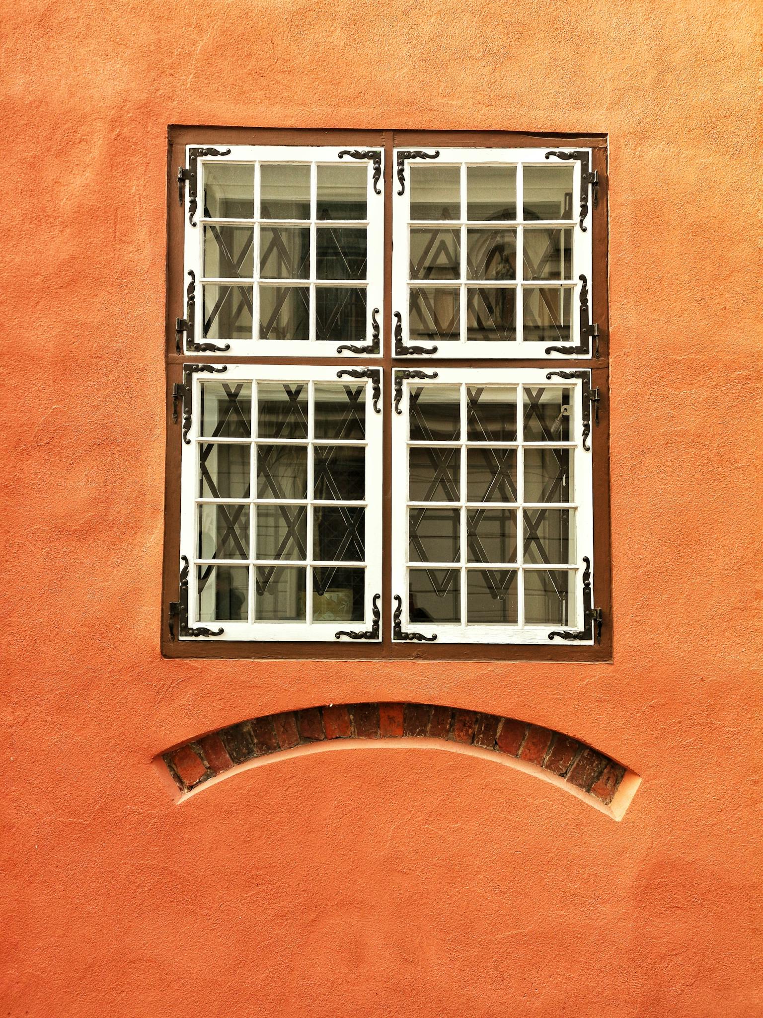 An antique window frame on a vibrant orange wall creates a vintage architectural look.